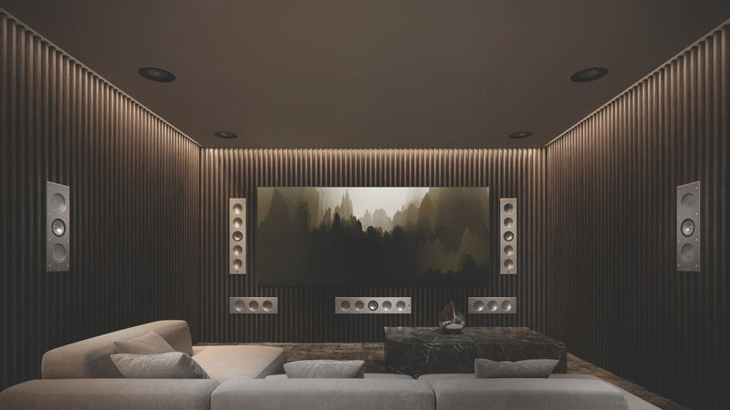 A sleek home theater setup with a large screen, displaying KEF architectural speakers  Ci5160RLM-THX speakers and smaller Ci3160RLM-THX speakers.