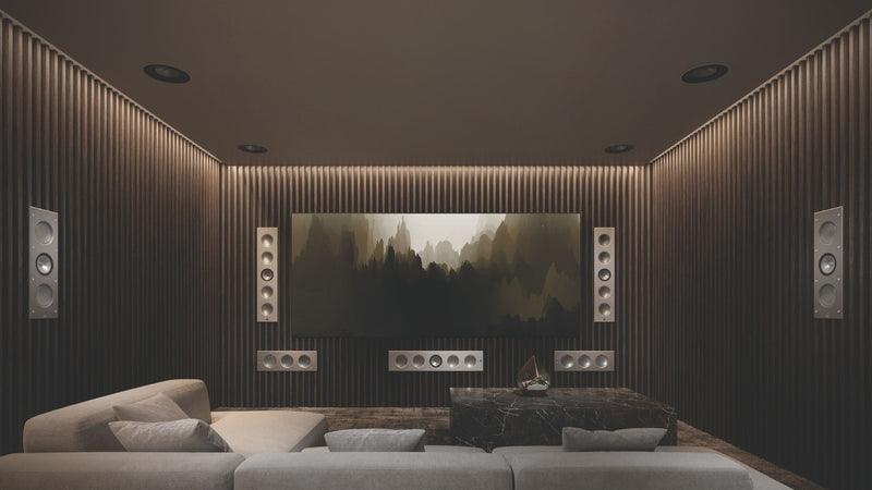 A sleek home theater setup with a large screen, displaying KEF architectural speakers  Ci5160RLM-THX speakers and smaller Ci3160RLM-THX speakers.