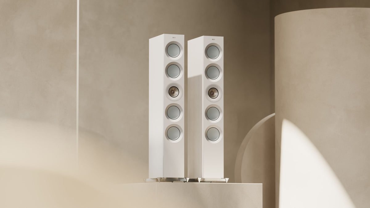 Pair of white The Reference floorstanding speakers with beige background.